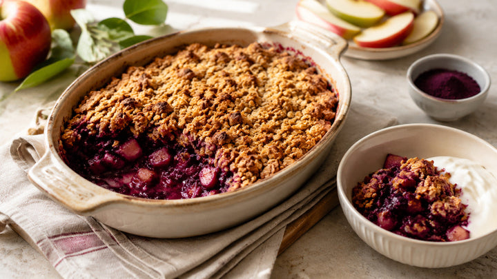 Warm açaí apple breakfast crumble with golden oat topping and yoghurt